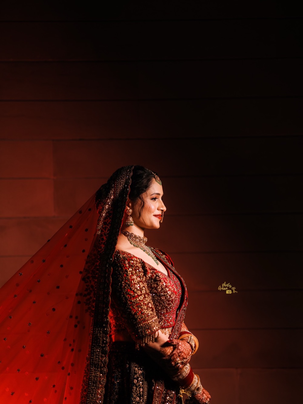 Bride in a red bridal lehenga with a long embroidered veil in dramatic light, styling by Fashion World Palampur