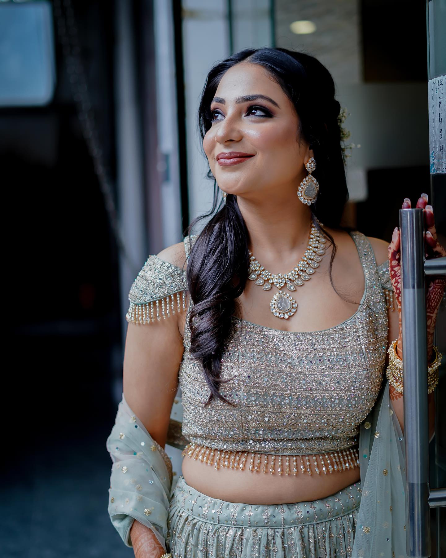 Bride in a sage-green lehenga with kundan jewellery and soft curls, makeup by Fashion World Palampur