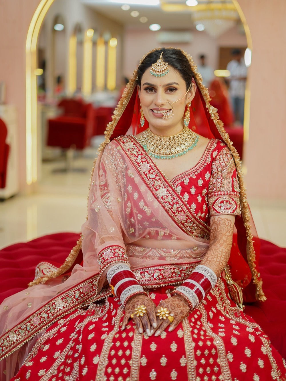 Bride in a red lehenga with full bridal jewellery, makeup and styling by Fashion World Palampur